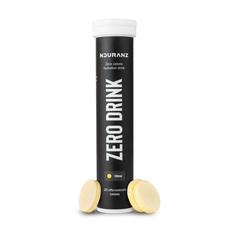 Nduranz Zero Drink - 20 šumečih tablet okus citrusov, črna cilindrična tubica z belim pokrovčkom, rožnatim krogom na belem ozadju.